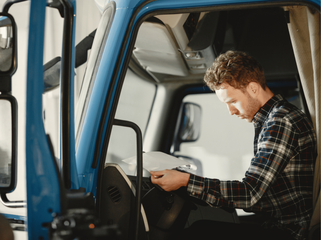 an hgv driver sits in the vehicle filling out a form
